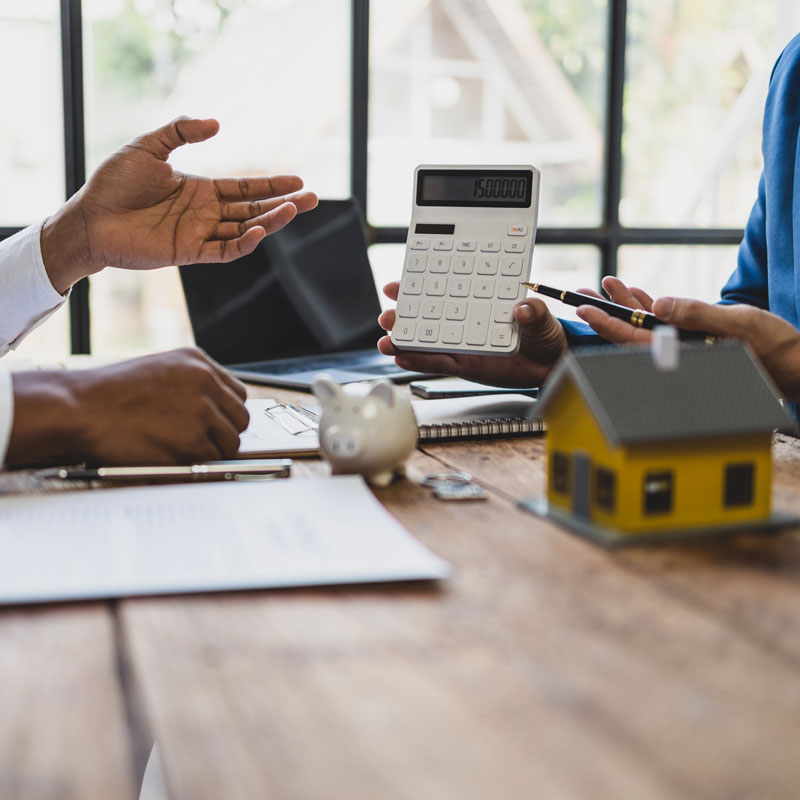 Beratungsgespräch mit Taschenrechner und Hausmodell – Finanzielle Planung beim Haus verkaufen Frankfurt